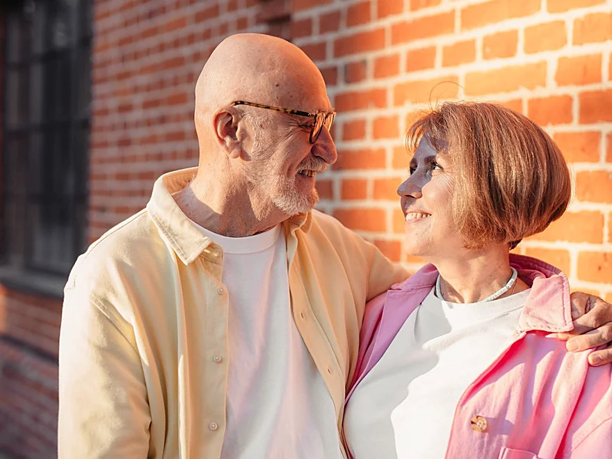 A couple in their seventies smiling together in the sun