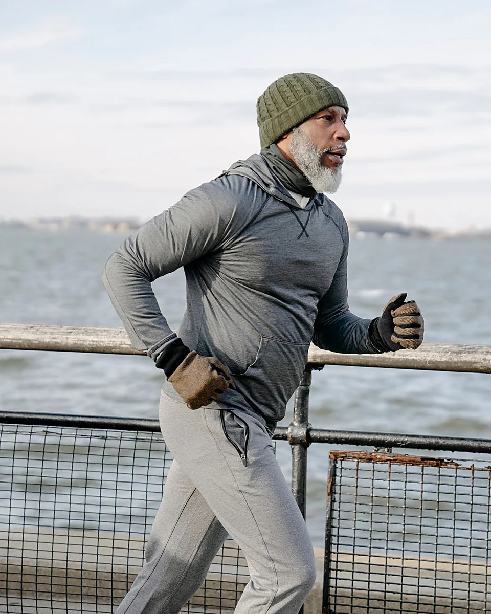 A man in his sixties running along a seafront railing on a cold, bright morning
