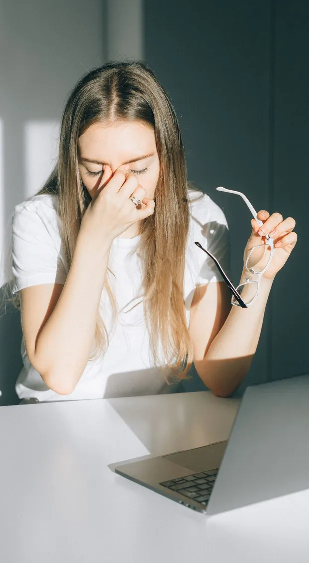 A woman rubbing tired eyes behind her glasses — the eye strain an eye supplement targets