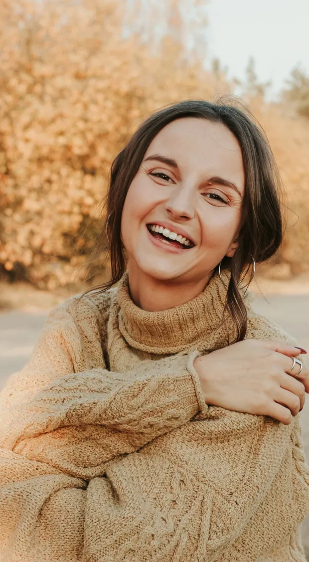 A woman laughing openly outdoors — healthy gums and fresh breath from oral care probiotics