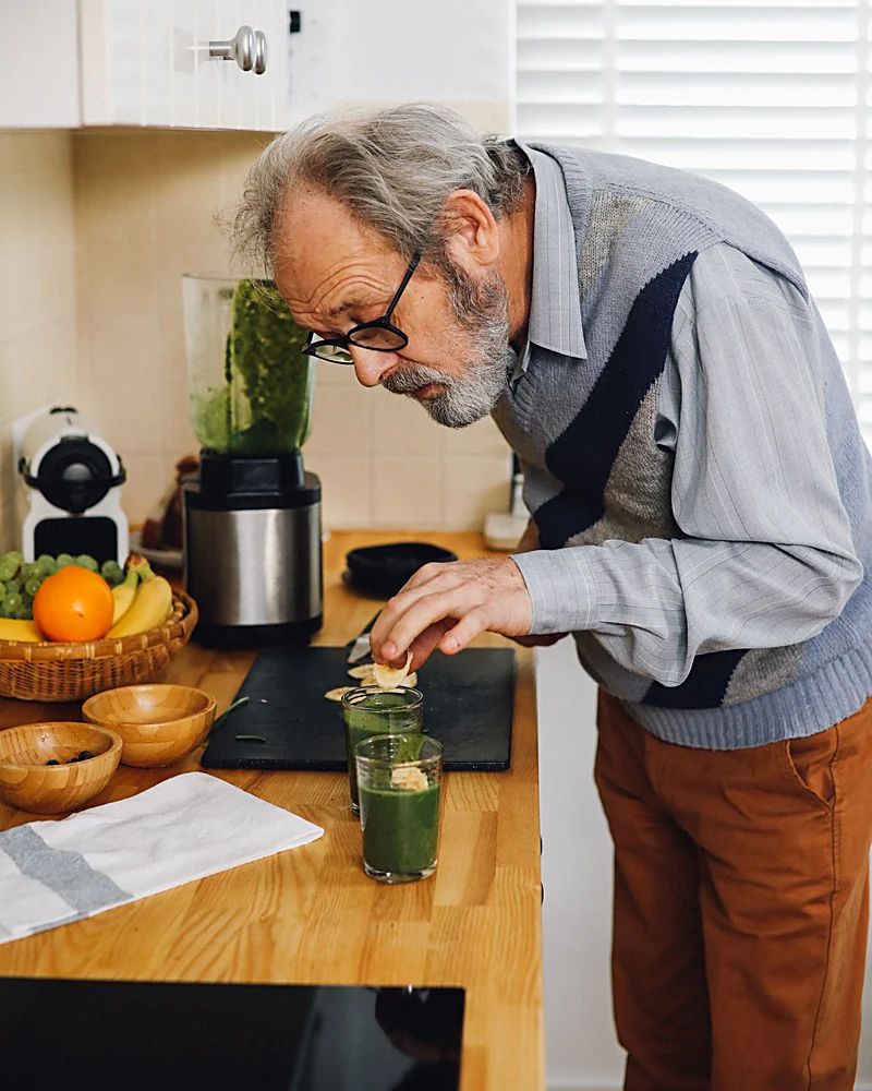A man in his sixties making a drink at his kitchen counter in the morning