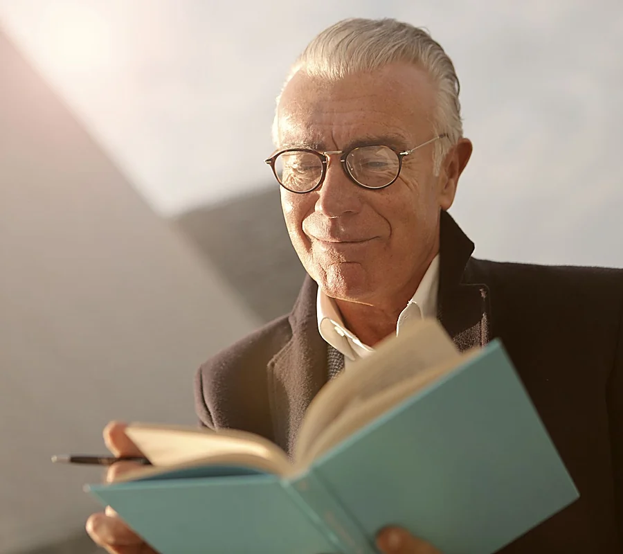 A man in glasses reading a notebook in warm afternoon light